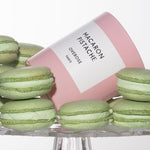 Macaron Pistachio candle surrounded by green macarons.