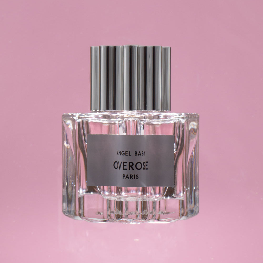 Perfume bottle with silver cap and clear glass body on a pink background