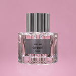 Perfume bottle with silver cap and clear glass body on a pink background