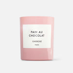 A pink candle with a label reading 'Pain au Chocolat' and 'Overose, Paris'.