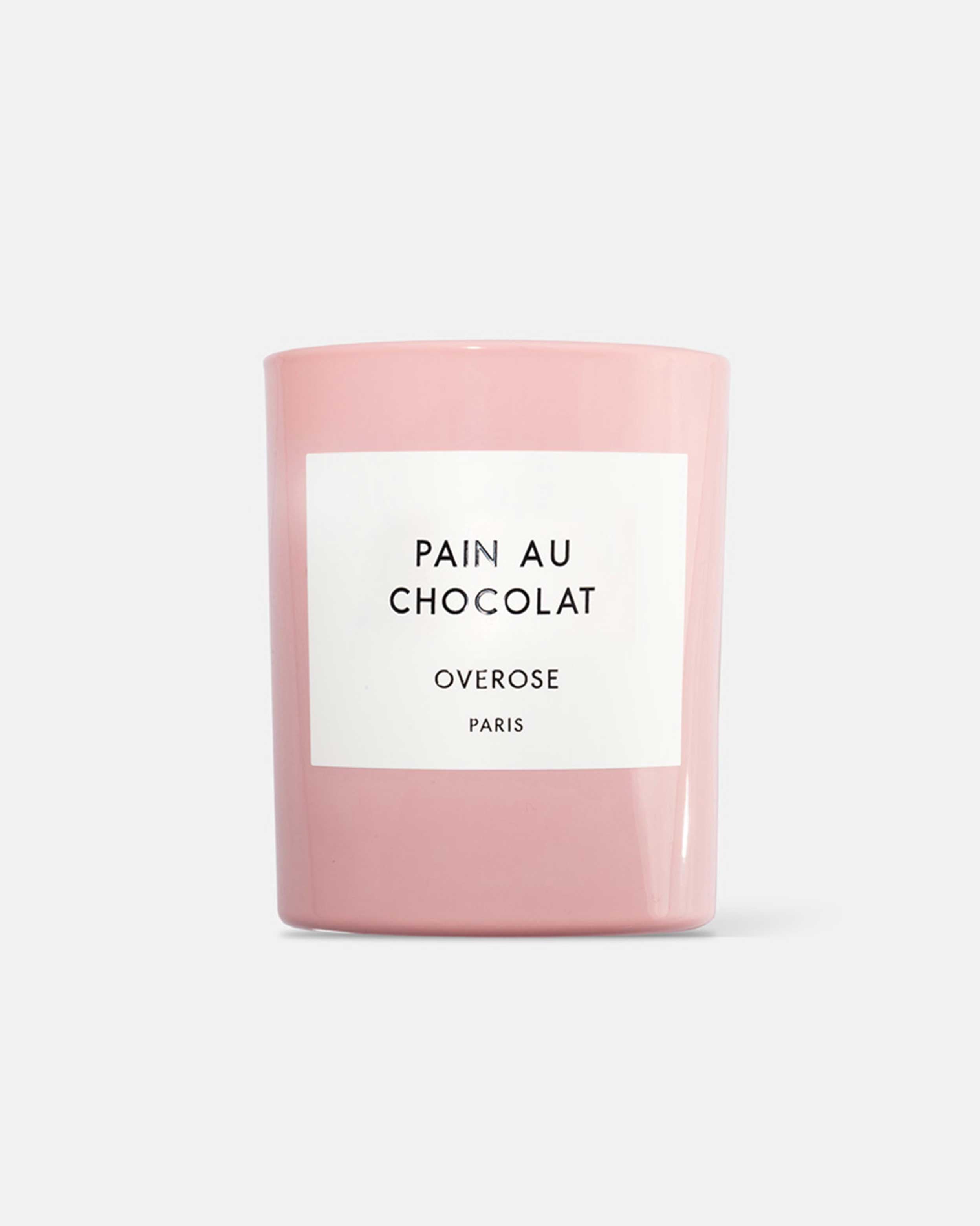 A pink candle with a label reading 'Pain au Chocolat' and 'Overose, Paris'.
