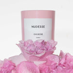 Pink candle with a label surrounded by pink flowers on a white background.