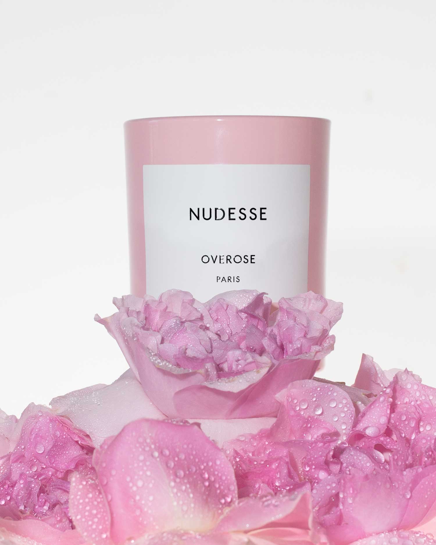 Pink candle with a label surrounded by pink flowers on a white background.