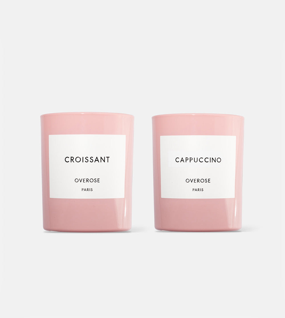Two candles, one labeled 'Croissant' and the other 'Cappuccino', each in a pink container with a white label.