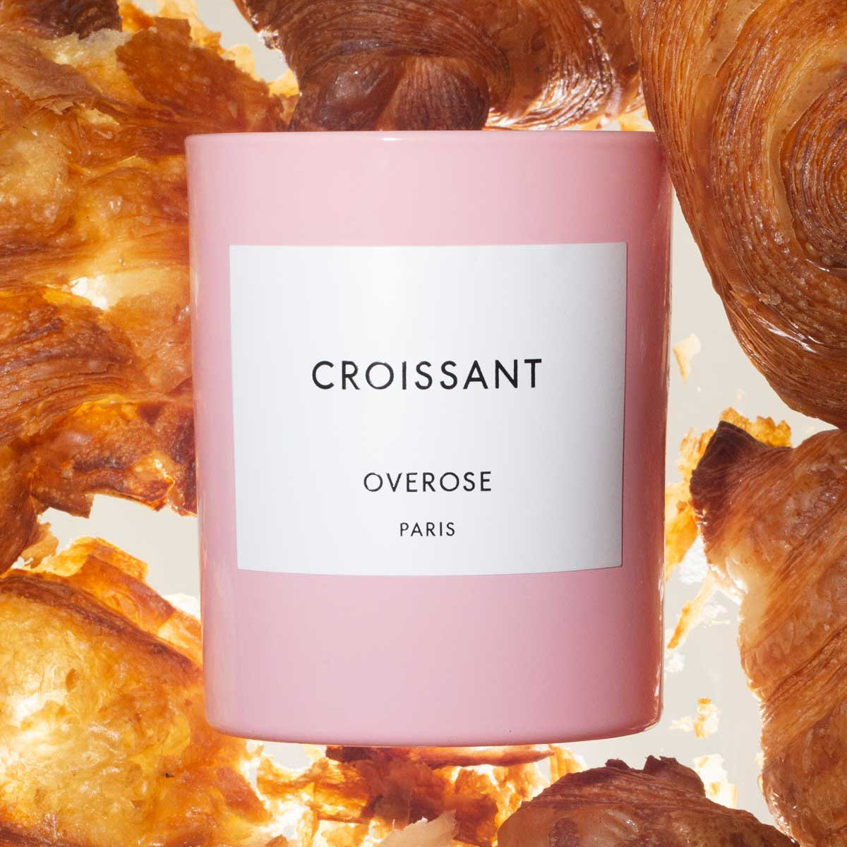 A pink candle with a white label that reads 'CROISSANT' and Croissants in the background