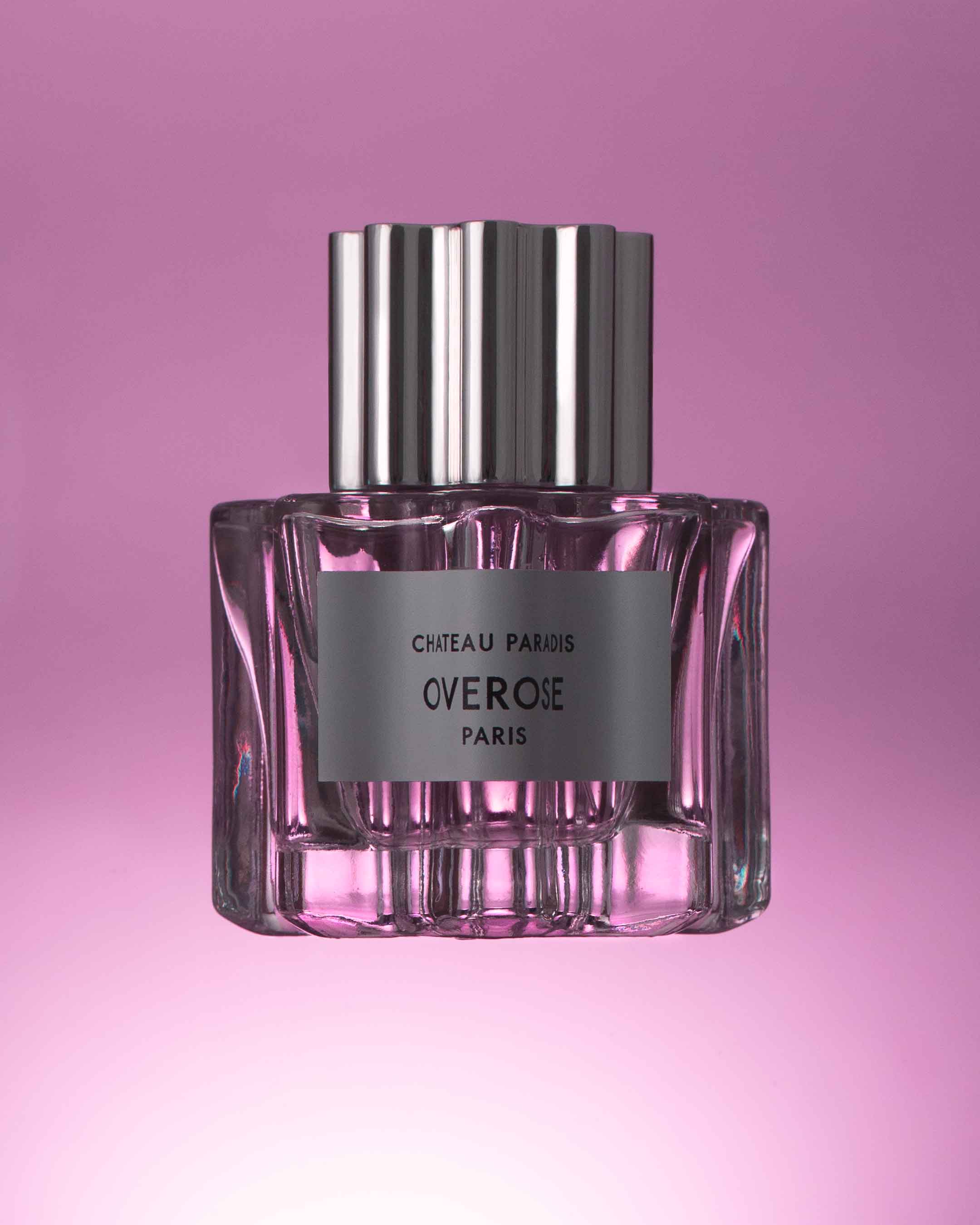 Perfume bottle with pink glass and silver cap on a gradient pink background