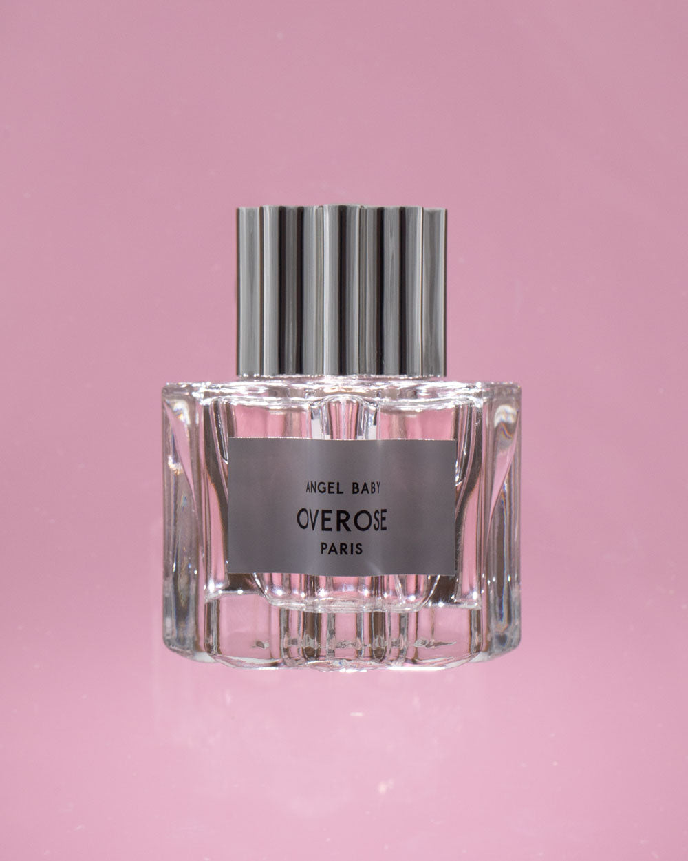 Perfume bottle with silver cap and clear glass body on a pink background