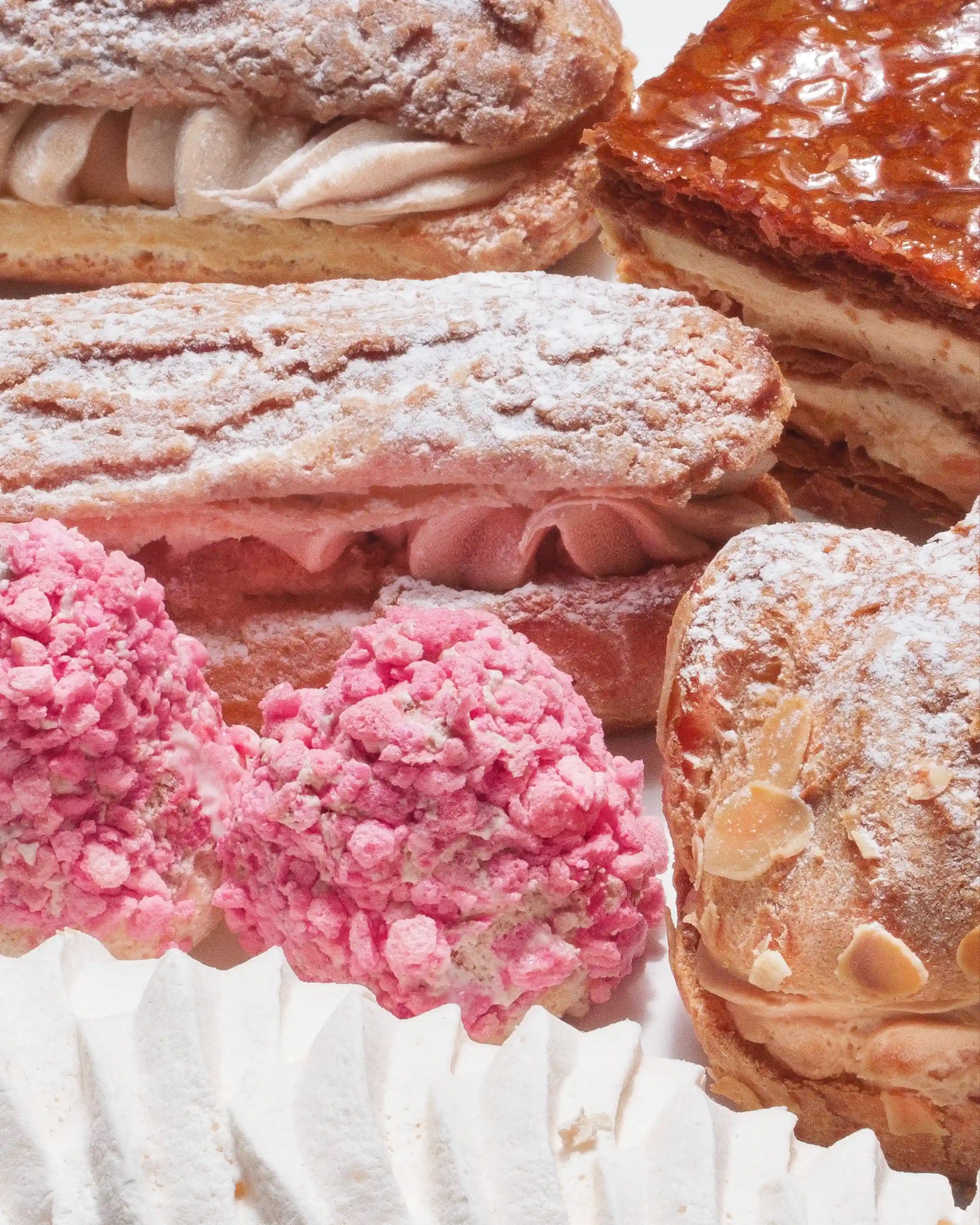 Assorted pastries including cream puffs and éclairs on a white surface.