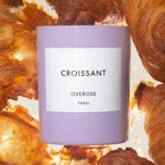 Croissant candle in purple jar in front of Croissants
