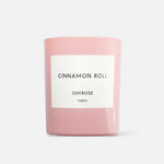 A pink cylindrical candle with the label 'Cinnamon Roll' and 'Overose Paris' on it.