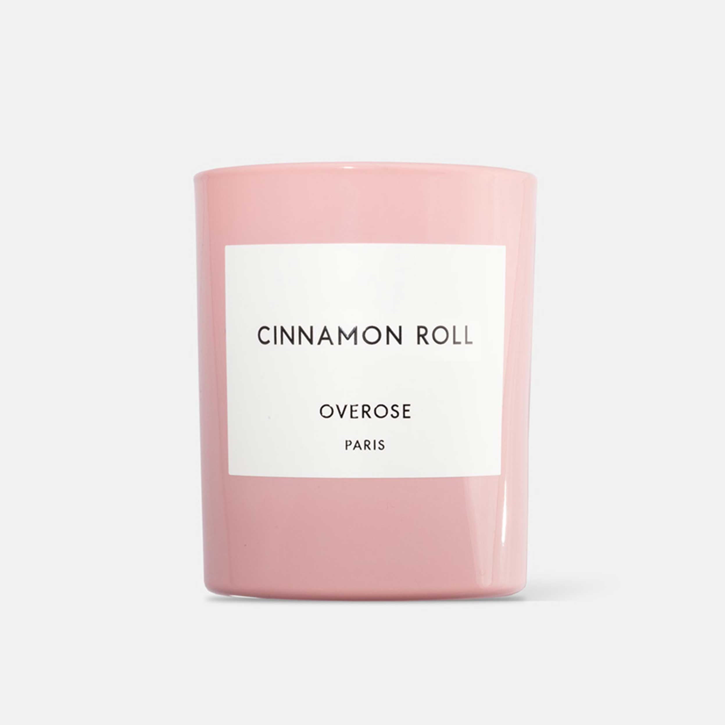 A pink cylindrical candle with the label 'Cinnamon Roll' and 'Overose Paris' on it.
