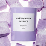 A lavender-colored candle jar labeled 'MARSHMALLOW LAVANDE OVERROSE PARIS' surrounded by lavender-colored sugar cubes on a white background.