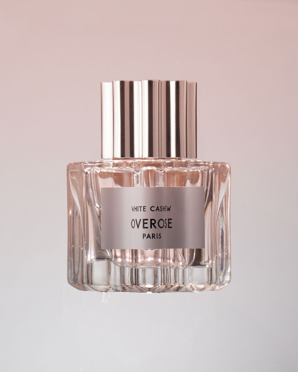 Perfume bottle with silver cap and clear glass body on a light pink background