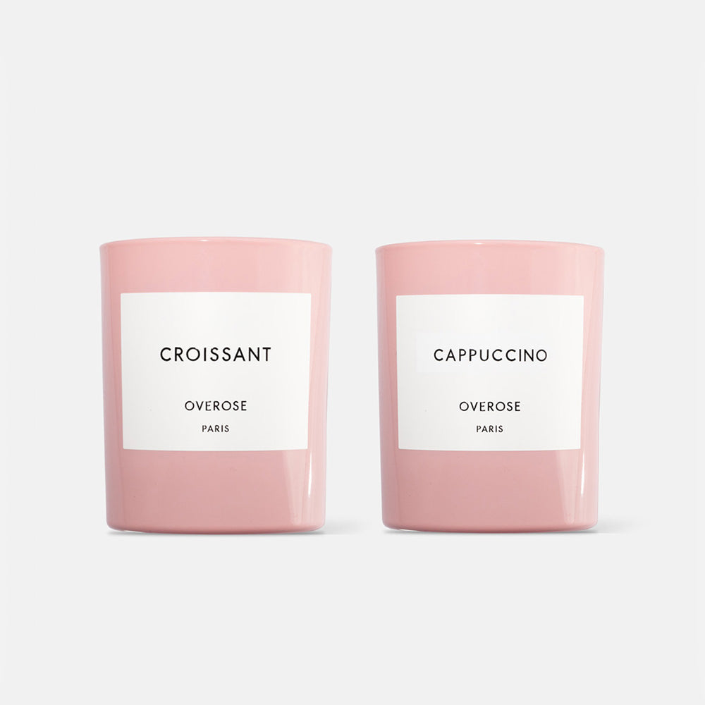 Two candles, one labeled 'Croissant' and the other 'Cappuccino', each in a pink container with a white label.