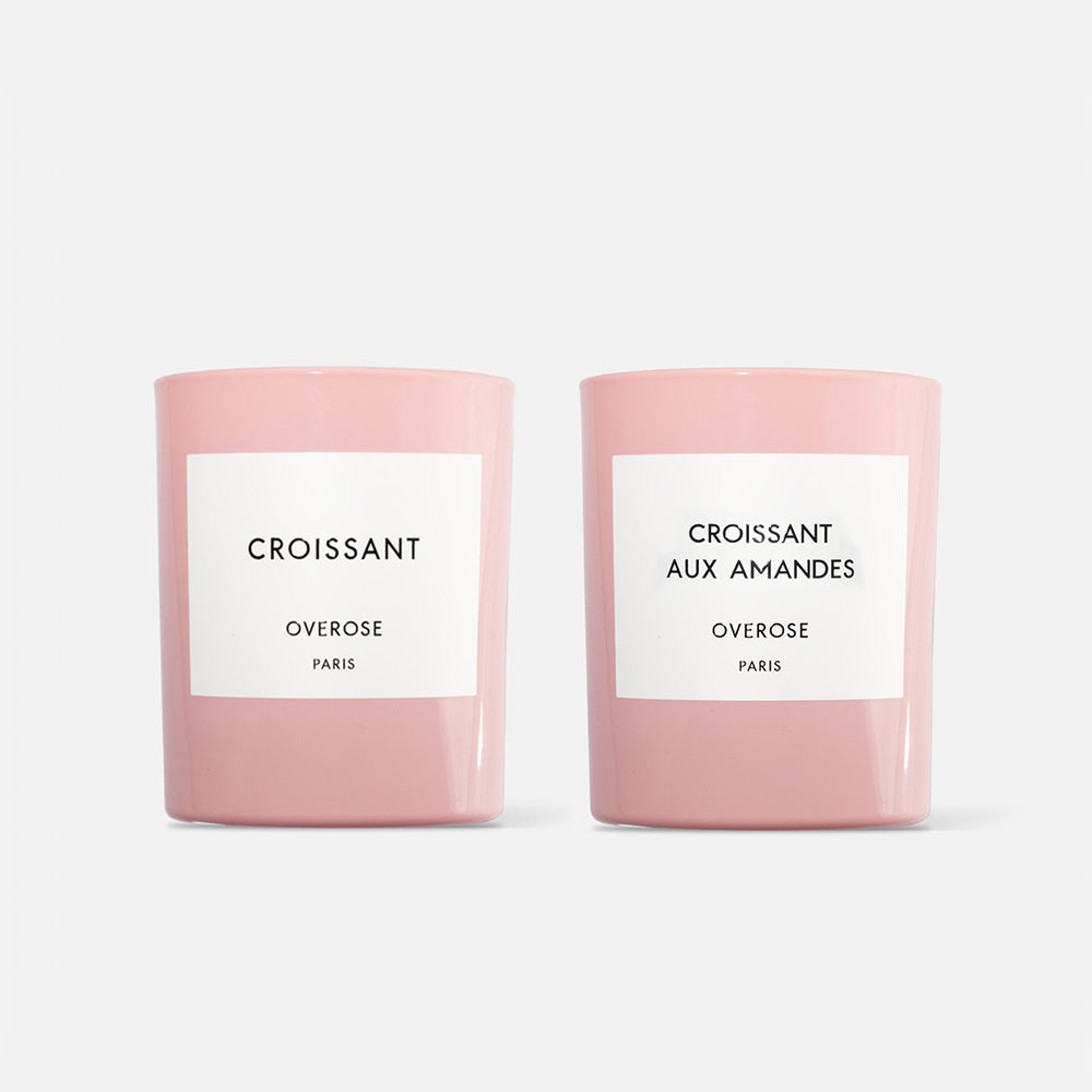 Two candles, one labeled 'Croissant' and the other 'Almond Croissant', both in pink jars