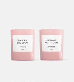 two pink candles with white labels on white background. one candle is "Pain au Chocolate" and the other is "Croissant aux Amandes"
