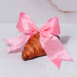 a croissant with a pink bow