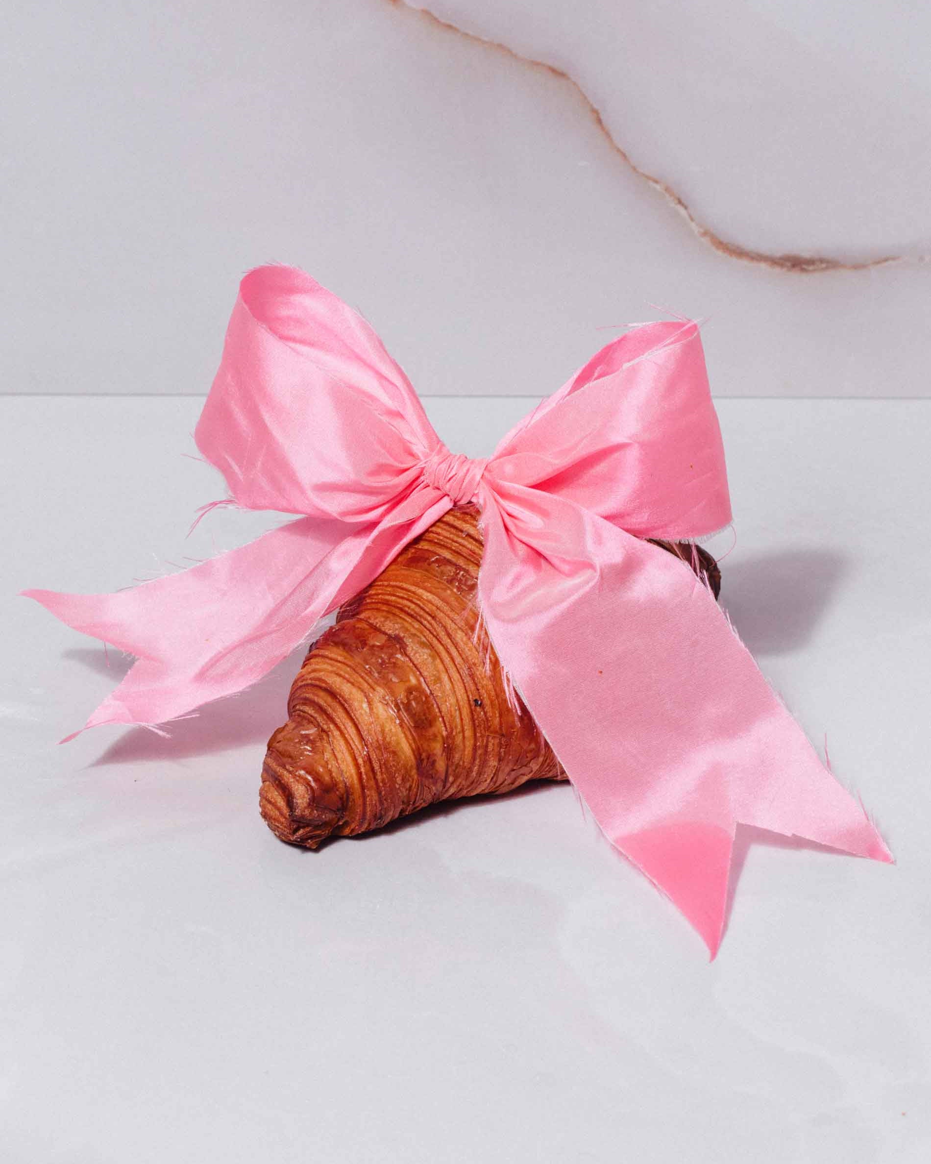 a croissant with a pink bow