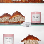 A shelf with 'Baked Vanilla Croissant' candles and vanilla croissant pastries