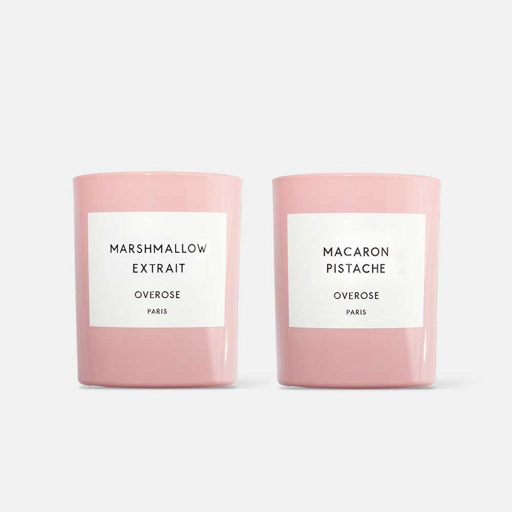 Two candles with pink glass jars, one labeled 'Marshmallow Extrait' and the other 'Macaron Pistachio'.